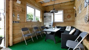 Een houten interieur met een eettafel, stoelen, een bank en een boekenkast.