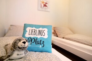 Un lit avec un oreiller sur lequel est écrit « LIEBLINGS Platz » et un jouet en peluche posé sur le lit.