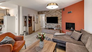 A modern living room with a flat-screen TV, a fireplace, and a stone accent wall.
