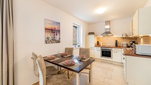 Een moderne keuken met een eethoek, met een tafel gedekt voor vier personen, een fornuis en een magnetron.