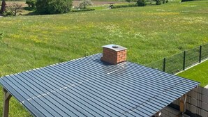 Vista de un campo verde con una estructura de techo metálico y una chimenea de ladrillo.
