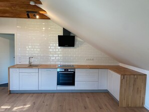 A modern kitchen with white cabinetry, a built-in oven, and a wooden countertop.