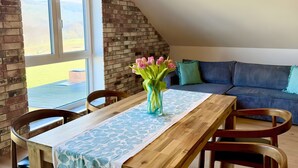 Un comedor con una mesa de madera, sillas, un florero y vistas a través de una ventana.