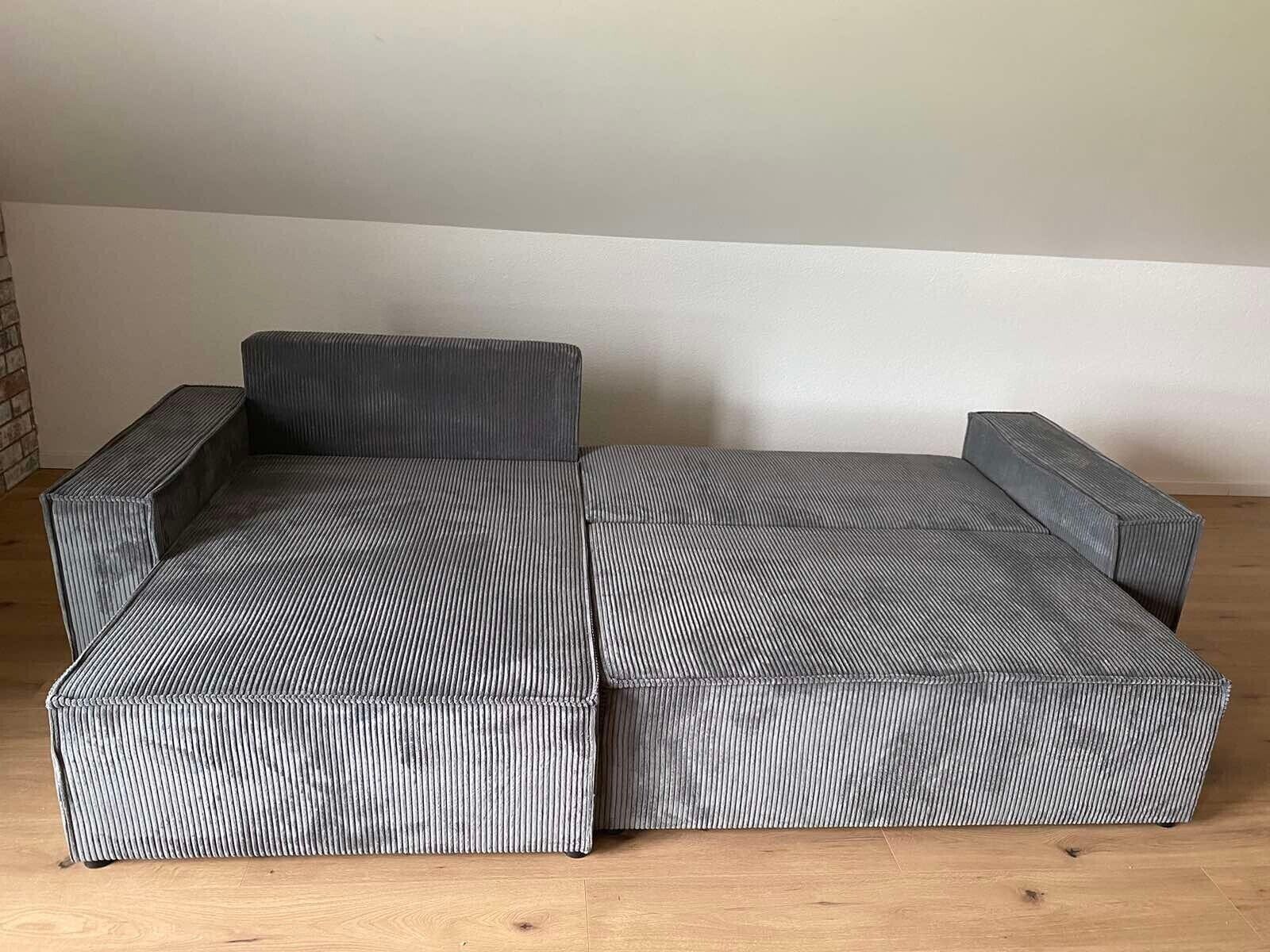 Un canapé modulable à la texture côtelée, un plancher en bois et un mur uni.