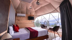 Una stanza a tenda con un letto, un tavolo, sedie, una TV e vista sull'esterno.