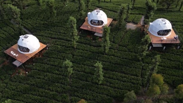 Tre edifici a forma di cupola in un paesaggio verde e rigoglioso.