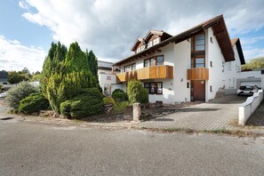 A two-story building with a sloped roof, wooden balcony railings, and a gravel driveway.
