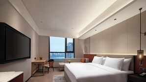 Una habitación de hotel moderna con una cama grande, un escritorio, una silla y un televisor.