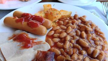 A plate with sausages, baked beans, and toast.