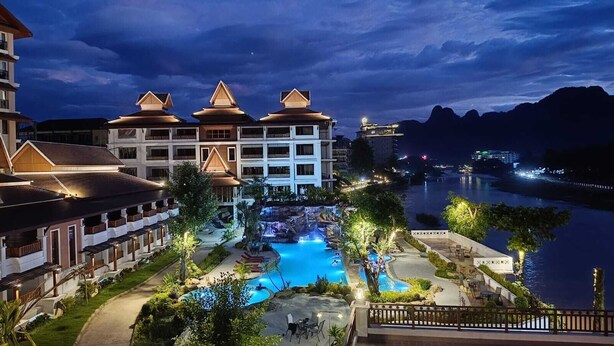A resort with a large pool, multiple buildings, and a view of a river at night. - Phubarn VimarnVangvieng Resort (Vang Vieng)