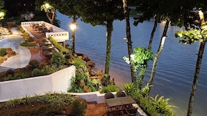 A riverside restaurant with outdoor seating, a stone pathway, and a view of the water. - Phubarn VimarnVangvieng Resort (Vang Vieng)