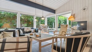 Ein geräumiger Wohnbereich mit Sofa, Sesseln, Tisch und Fernseher.
