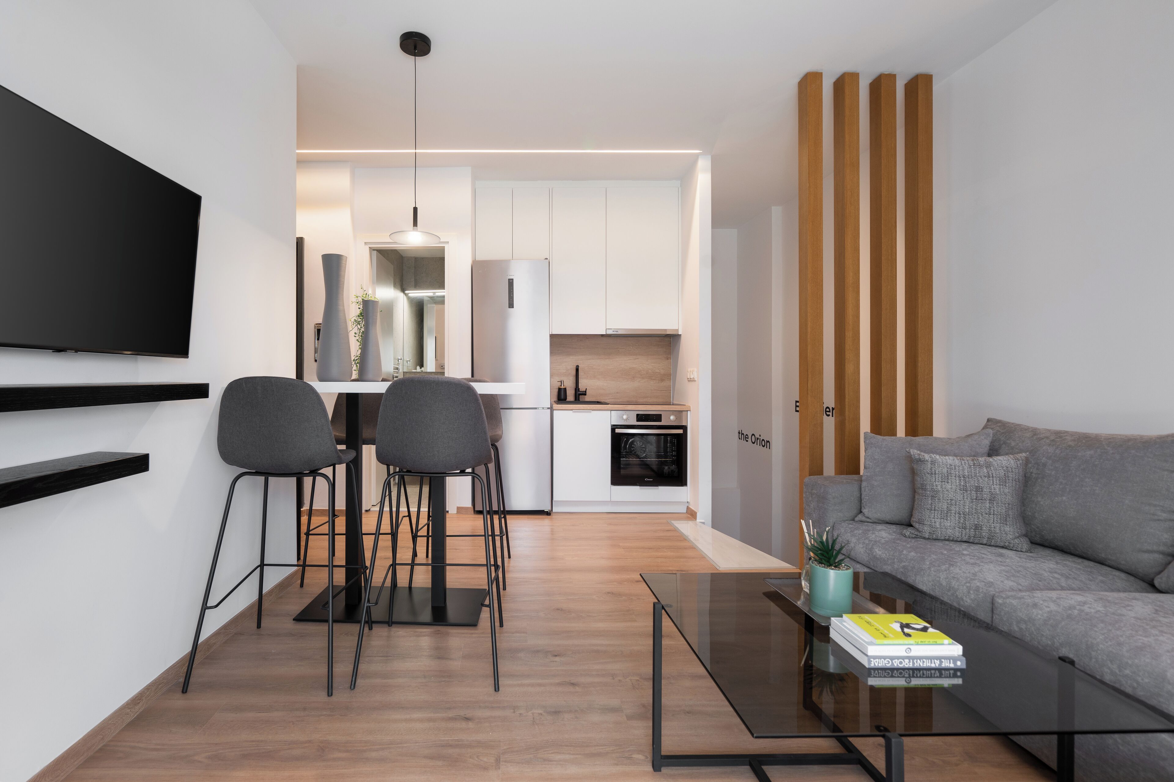 A modern living room with a grey sofa, a coffee table, and a TV mounted on the wall.