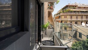 Un balcón con una silla, una mesita y una planta en maceta.