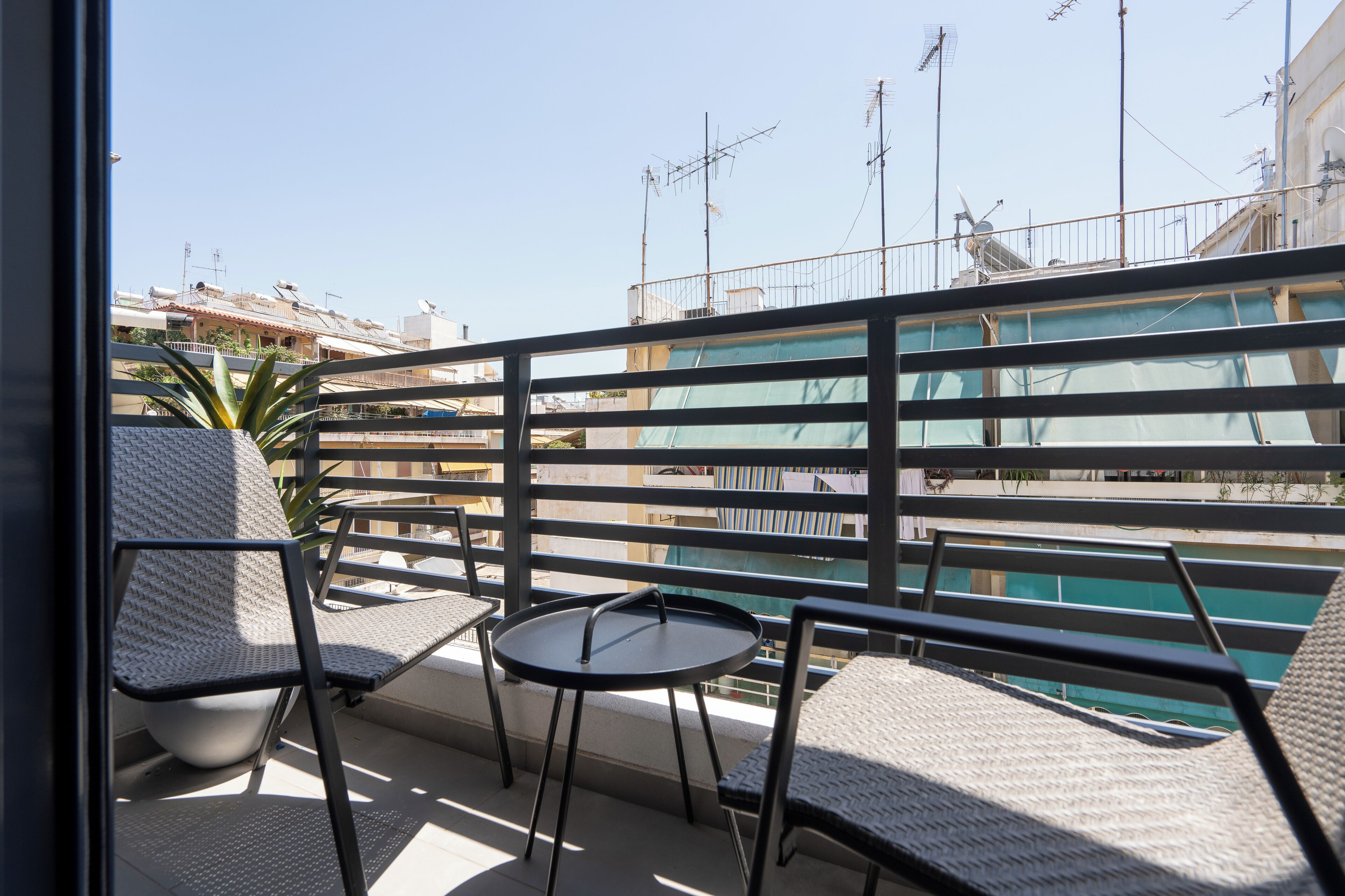 A balcony with two wicker chairs and a small round table, overlooking a pool area.