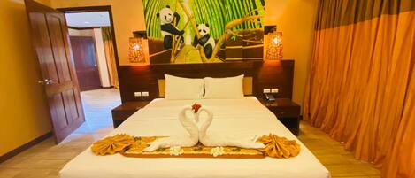 A hotel room with a large bed, a mural of pandas on the wall, and a swan-shaped centerpiece.