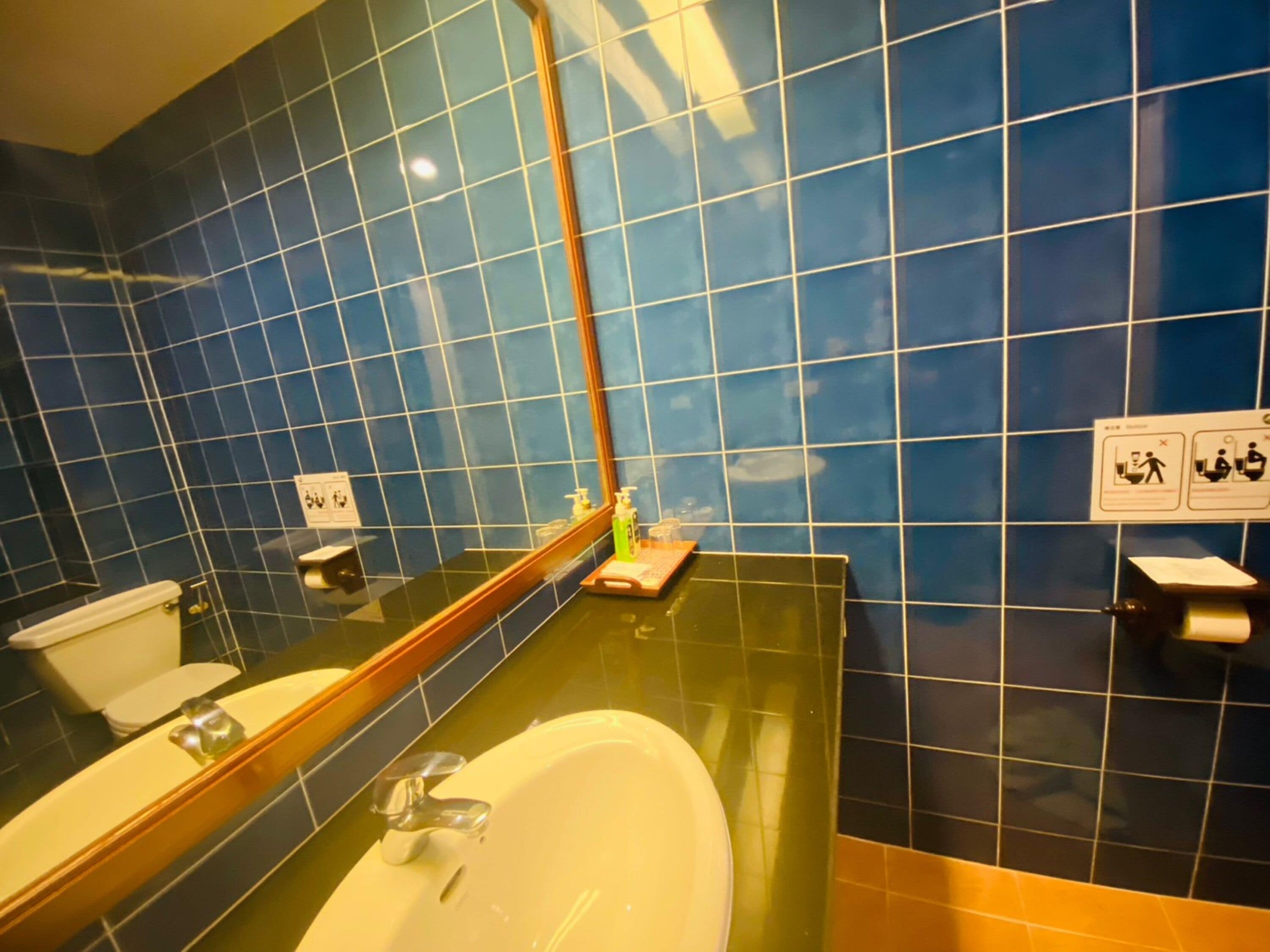 Een badkamer met een witte wastafel, een spiegel en blauwe betegelde wanden.