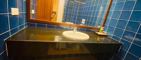 A bathroom with blue tiles, a black countertop, and a white sink.
