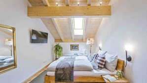 A bedroom with a bed, bedside table, lamp, and a TV on the wall. - Vacation apartment Bergparadies 154 sqm for max. 4 persons (Obing)
