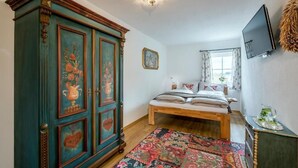 Ein Schlafzimmer mit einem Bett, einem Kleiderschrank, einem Fernseher und einem Fenster mit Vorhängen.