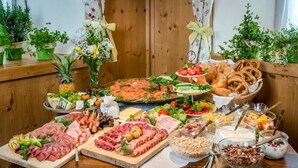 Une table de buffet proposant une variété d’aliments, notamment des viandes, des fromages, des fruits et des desserts.