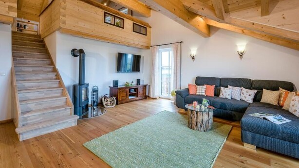 Un vaste espace de vie comprenant un escalier en bois, un ensemble de canapés, une cheminée et un téléviseur.