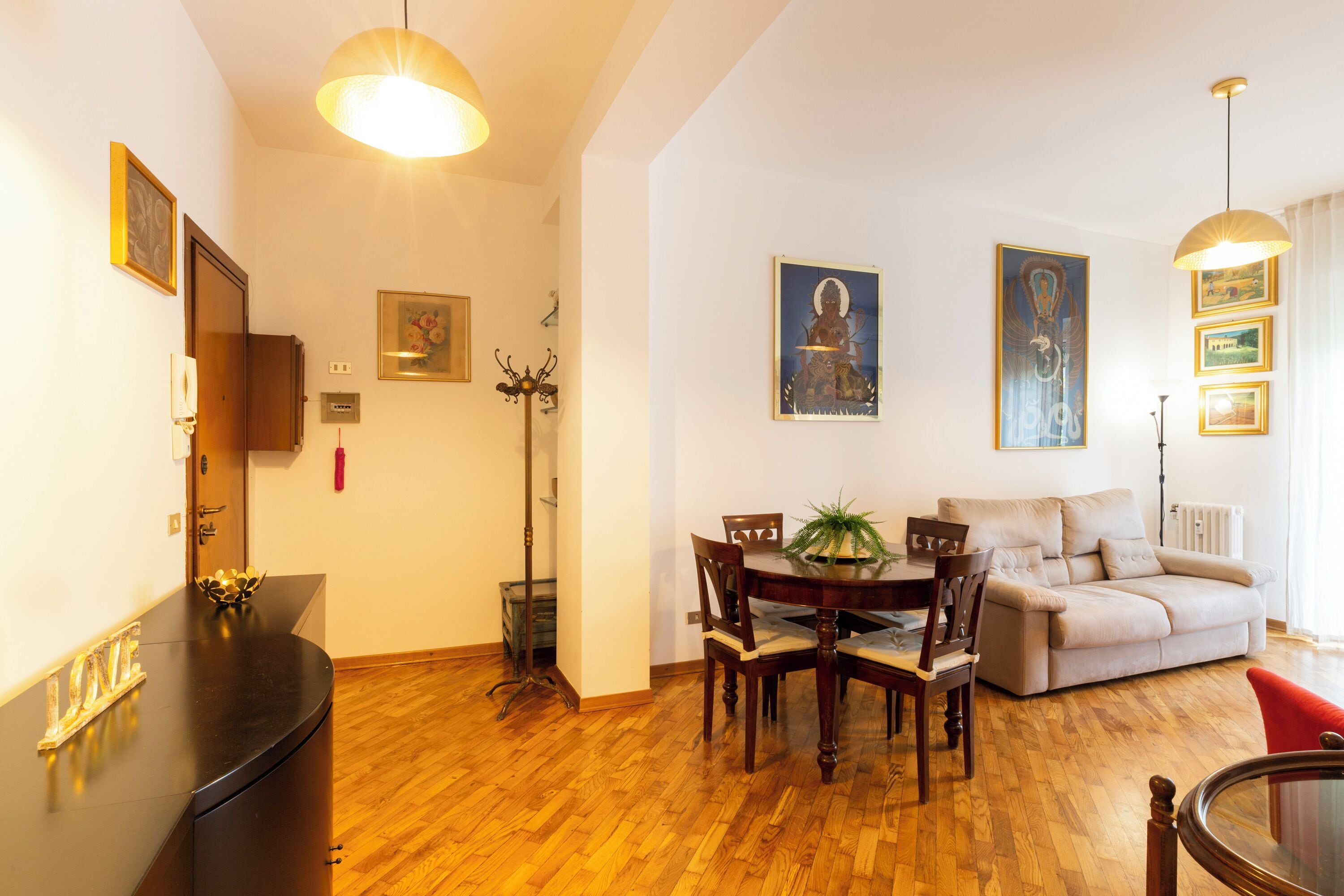 A living room with a dining table, sofa, and wooden flooring.