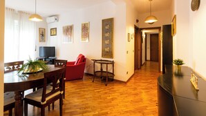 Ein Essbereich mit einem Holztisch, Stühlen, einer roten Couch und einem Fernseher.