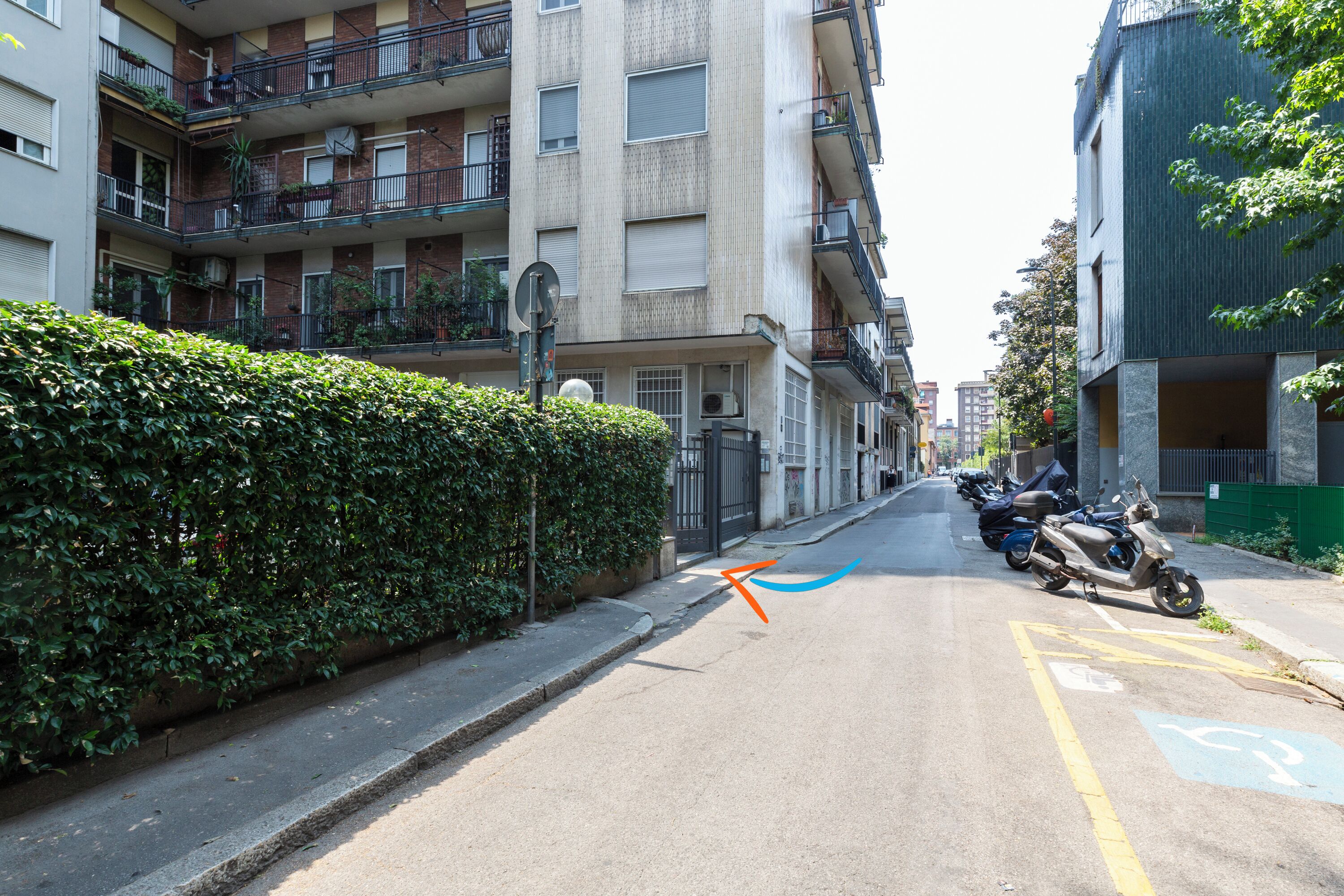 A street with parked motorcycles, a bicycle lane, and multi-story residential buildings with balconies.