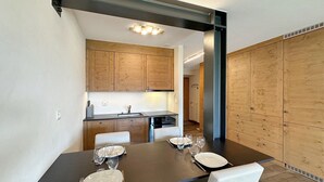 Una cocina moderna con armarios de madera y una zona de comedor con una mesa dispuesta para cuatro.