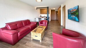 Un salón con sofás de cuero rojo, una mesa de centro de madera y un cuadro de un paisaje montañoso.