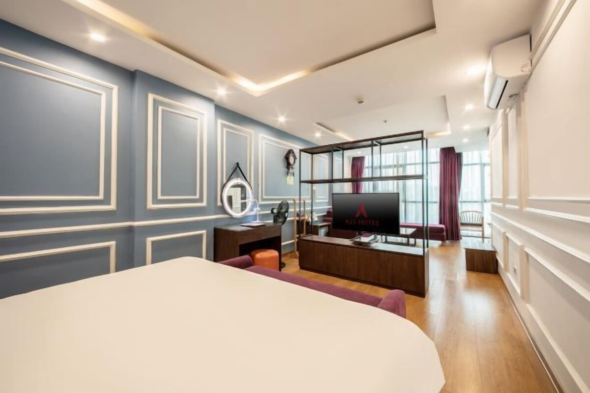 Une chambre d’hôtel moderne dotée d’un grand lit, d’un bureau avec un ordinateur, d’une télévision et d’un coin salon offrant une vue sur la ville.