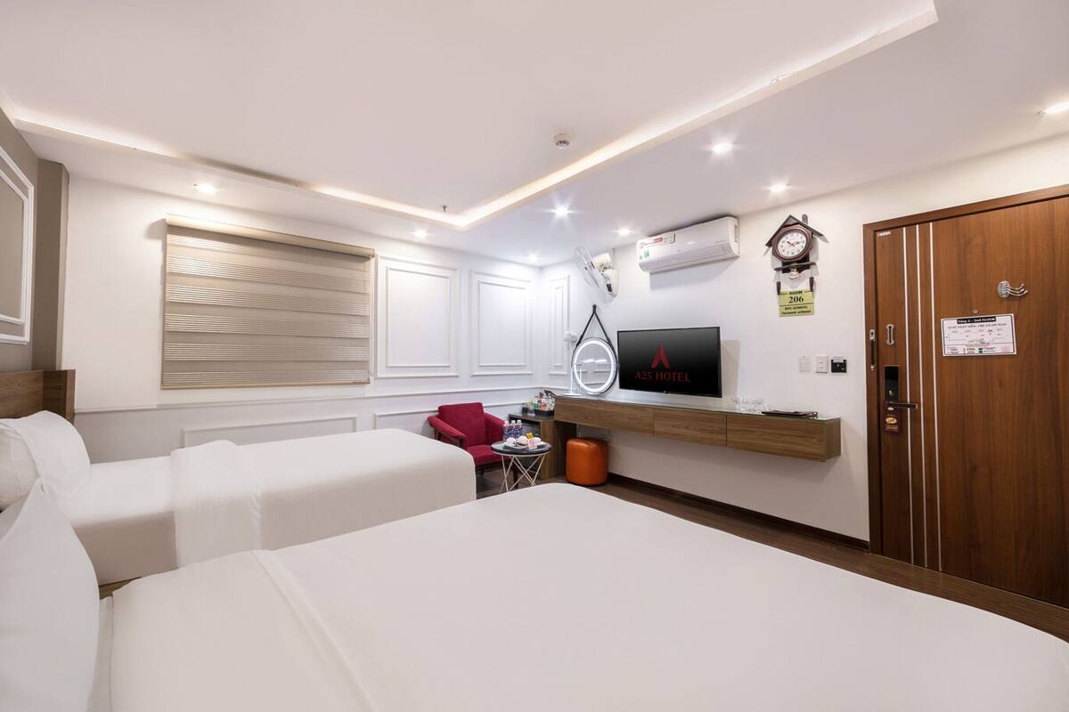Una habitación de hotel con dos camas, un televisor, un reloj y un armario de madera.