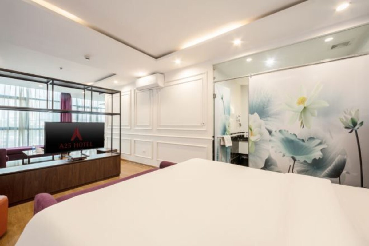 Habitación de hotel con una cama grande, un escritorio con computadora, un televisor y una pared decorada con motivos florales.