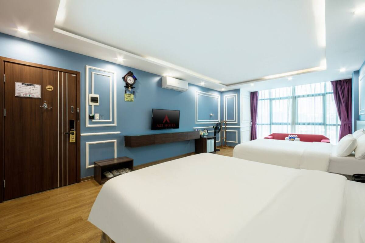 Habitación de hotel con dos camas, un televisor, un reloj y un armario de madera.