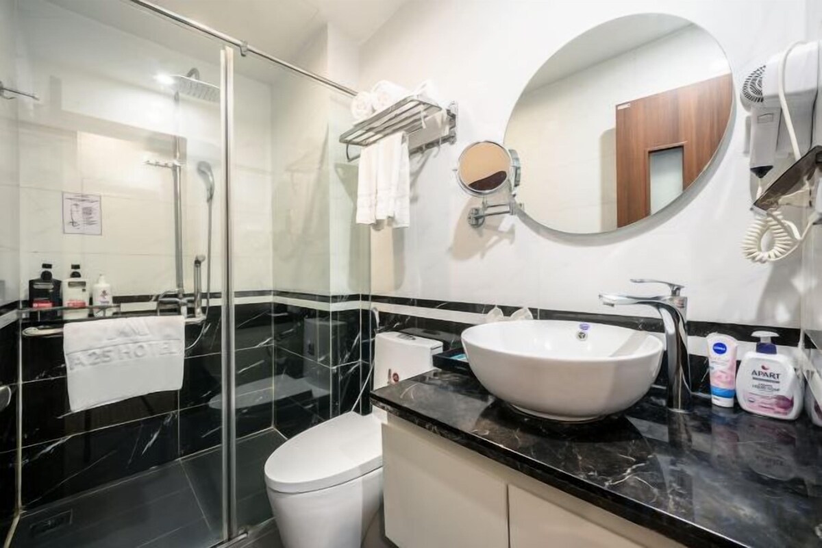 Een moderne badkamer met een douchecabine van glas, een witte wastafel en een grote spiegel.