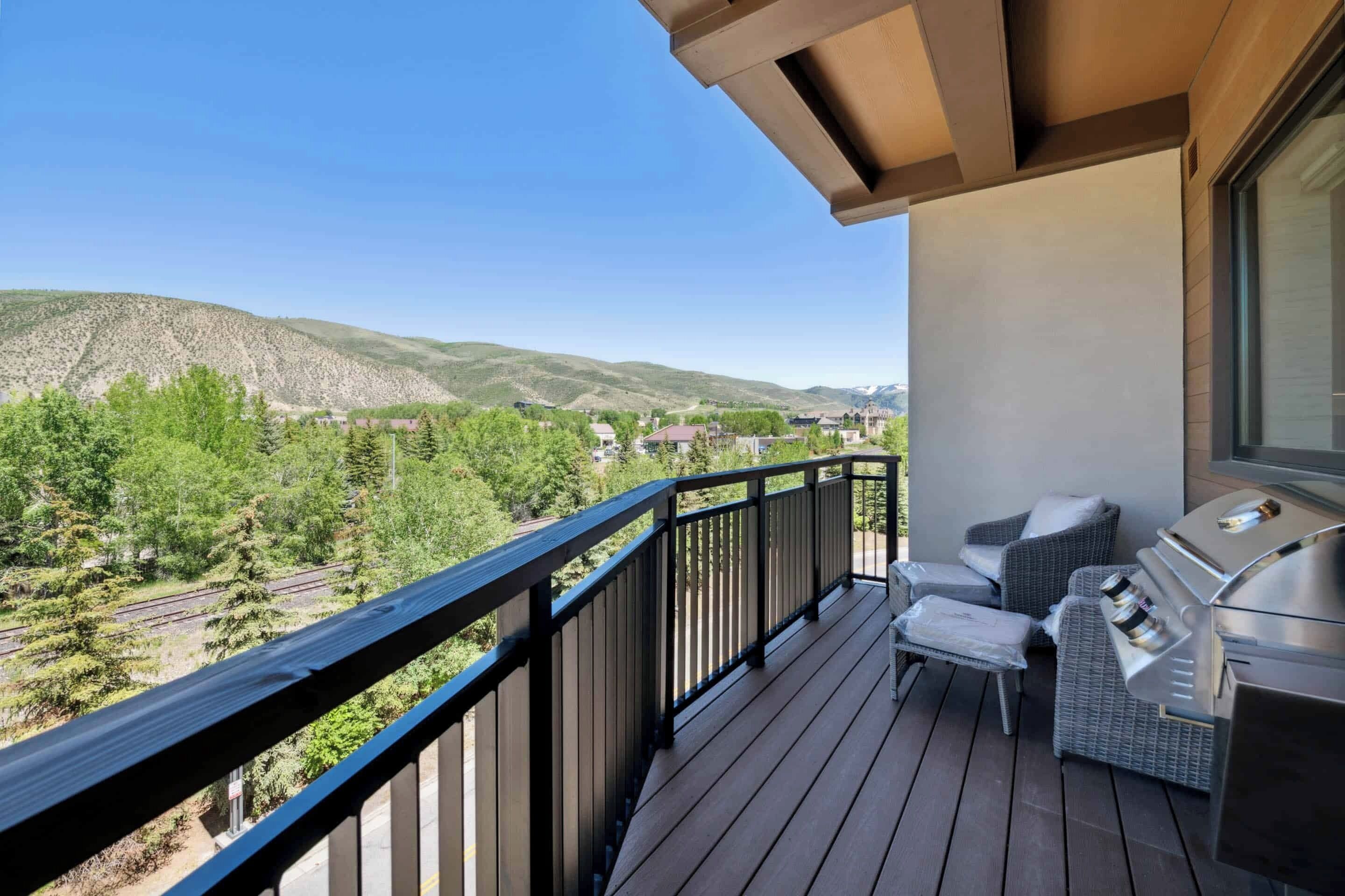 A balcony with a view of mountains and a grill.