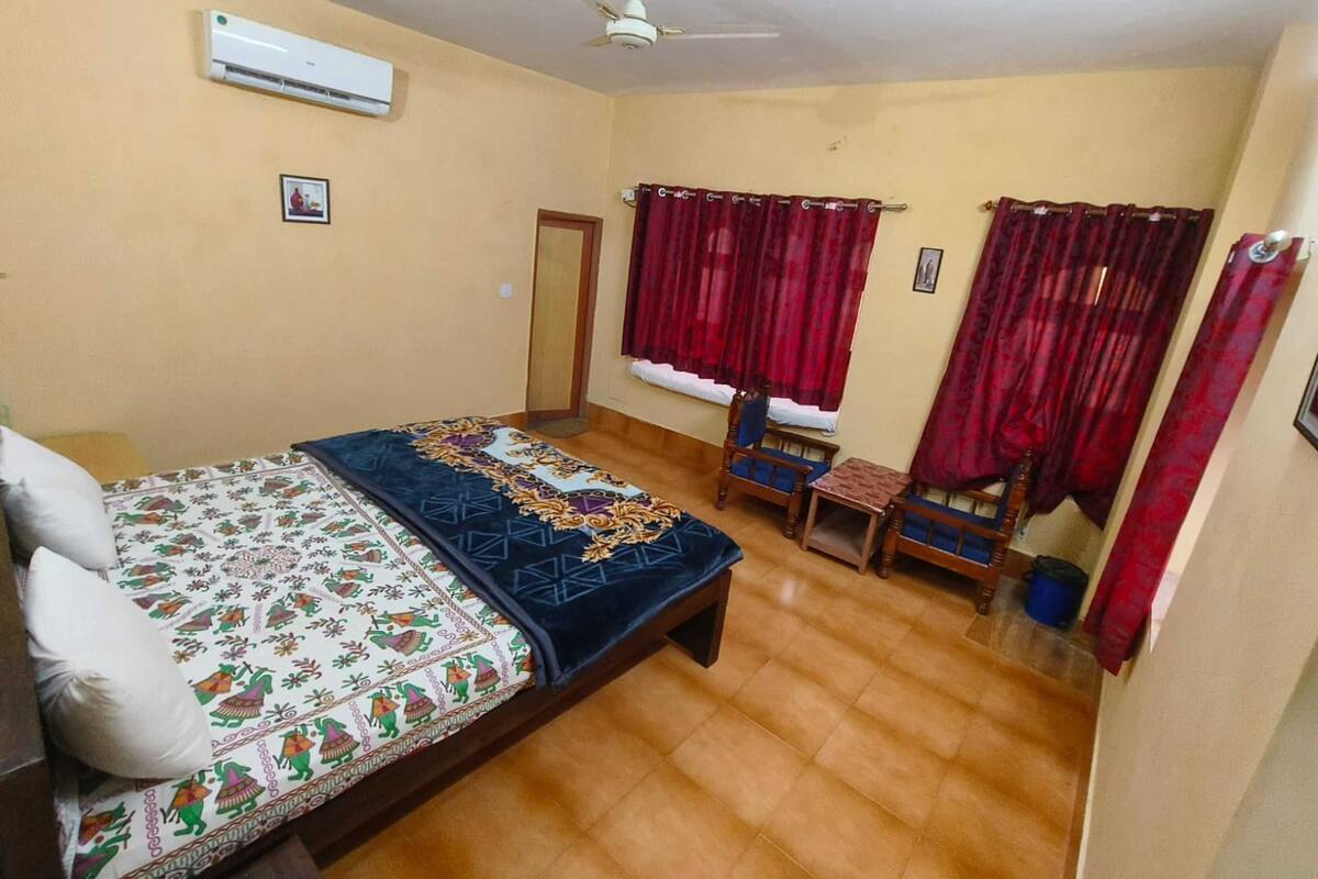 Een slaapkamer met een bed, een plafondventilator, een airconditioner en rode gordijnen.