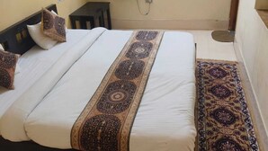 A bedroom with a bed, a wardrobe, a mirror, a curtain, and a small table.