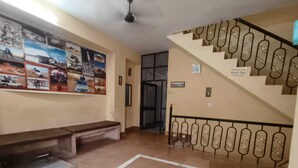 A staircase with a metal railing, a bench, and a wall with various posters.