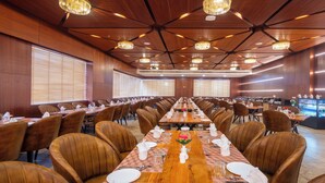 A large conference room with long tables, brown leather chairs, and chandeliers. - Hotel Kaushal Regency (Refinery Road Pachpadra) (Pachpadra)