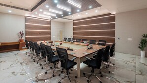 A conference room with a long table, black chairs, and a wooden panel wall. - Hotel Kaushal Regency (Refinery Road Pachpadra) (Pachpadra)