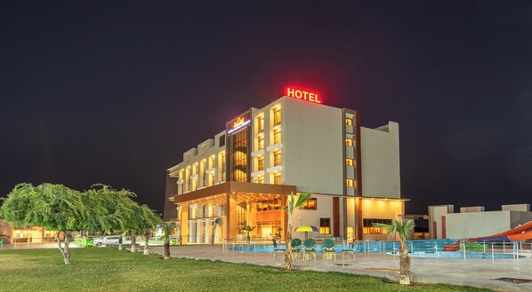 A modern hotel with a prominent 'HOTEL' sign, a swimming pool, and a well-lit outdoor area. - Hotel Kaushal Regency (Refinery Road Pachpadra) (Pachpadra)