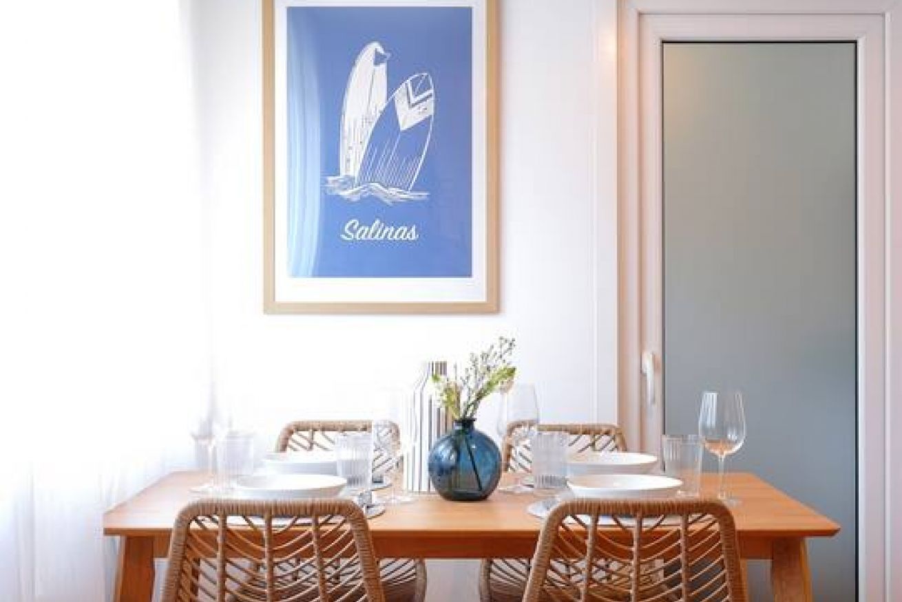 Un tavolo da pranzo con sedie, un vaso con fiori e un quadro appeso al muro.