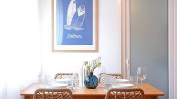 Un tavolo da pranzo con sedie, un vaso con fiori e un quadro appeso al muro.
