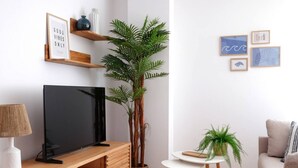 A modern living room with a flat-screen TV, wooden entertainment unit, a potted plant, a small round table, and a sofa. - 11A02 Casa RTPG  6p (Castrillon)