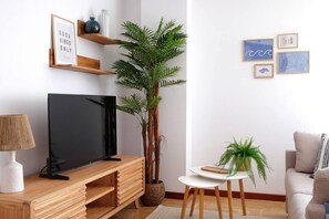A modern living room with a flat-screen TV, wooden entertainment unit, a potted plant, a small round table, and a sofa. - 11A02 Casa RTPG  6p (Castrillon)