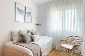 A bedroom with a bed, pillows, a chair, and two framed wall art pieces. - 11A02 Casa RTPG  6p (Castrillon)