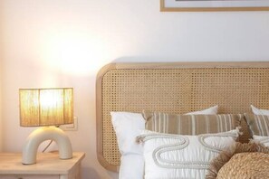 A bed with a woven headboard, a bedside lamp, and several pillows. - 11A02 Casa RTPG  6p (Castrillon)