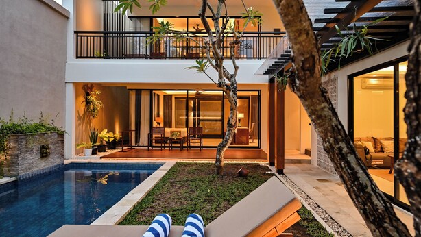 Ein modernes Haus mit Schwimmbad, Essbereich und Lounge mit gestreiften Handtüchern.